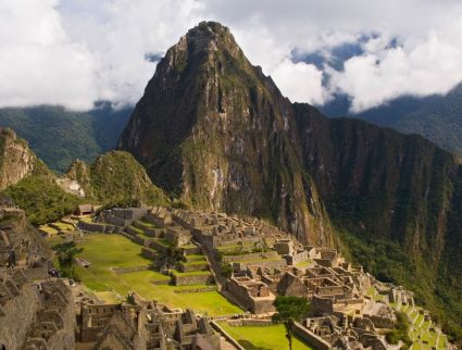 Traveler looks over the ancient Incan ruins of Machu Picchu, capturing the breathtaking views on a Machu Picchu trip.