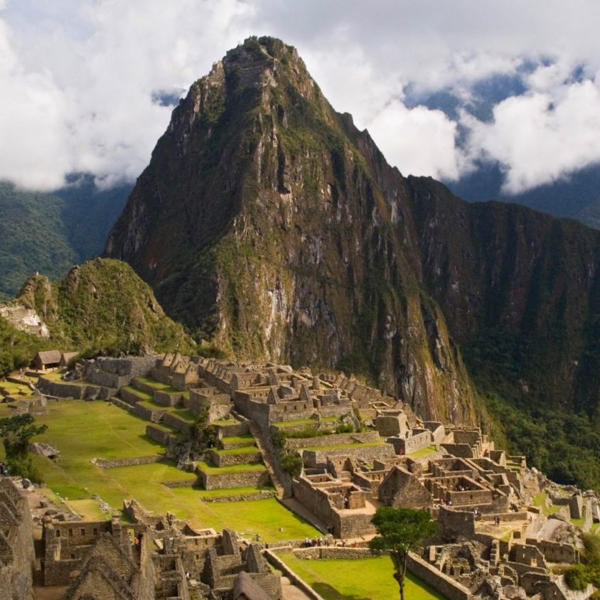 Traveler looks over the ancient Incan ruins of Machu Picchu, capturing the breathtaking views on a Machu Picchu trip.