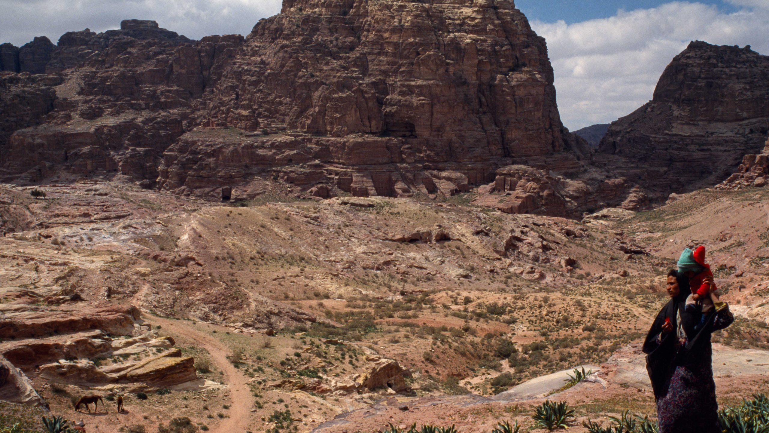 A Bedouin carries a child home amidst the spectacular landscapes of ancient Petra, Jordan.
