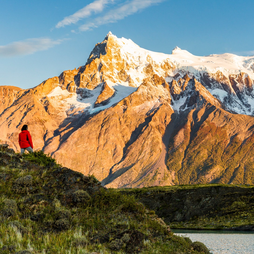 A hiker admires sunrise on Cerro Paine Grande, Torres del Paine, Chile