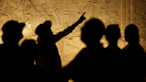 Silhouetted tour guide pointing at ancient Egyptian carvings, highlighting solar eclipse symbols on an Egypt tour.